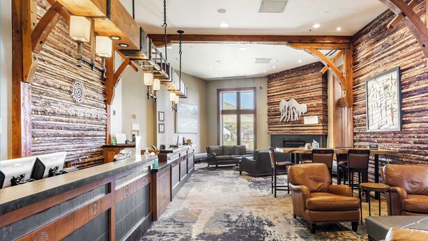 Un área de recepción con pared de madera, mostrador y asientos.