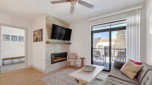 Una sala de estar moderna con chimenea, televisor de pantalla plana, sofá y mesa de comedor.