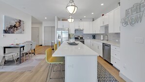 Una cocina moderna con armarios blancos, una isla central y un colgador de luces.