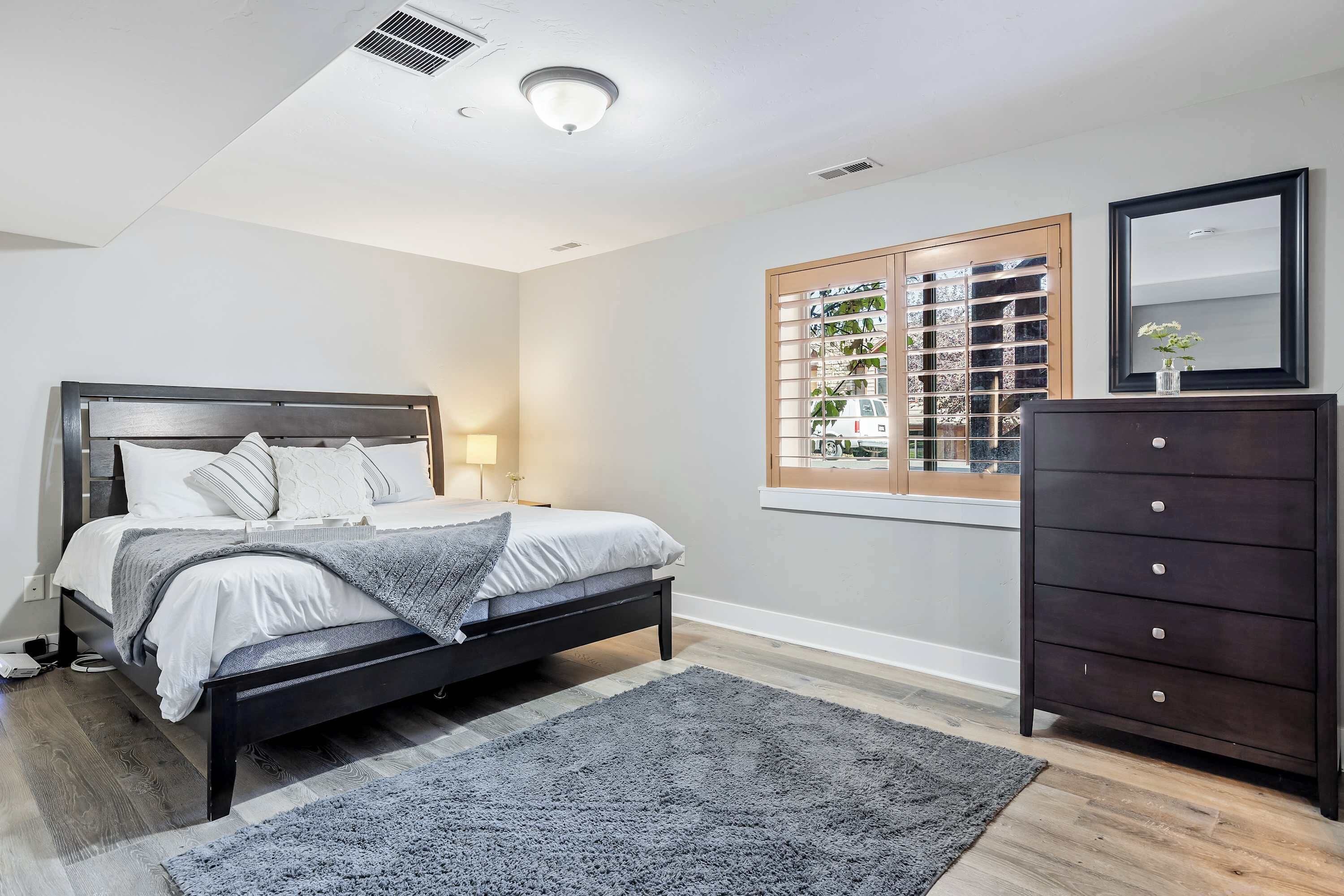 Une chambre à coucher avec un lit, une commode et une fenêtre équipée de stores.