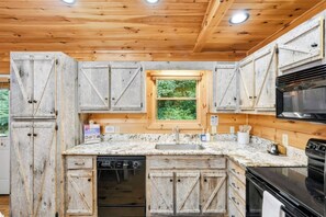 A kitchen with wooden cabinets, a window, a sink, a dishwasher, and a stove. - Cabin in Blue Ridge Hot Tub, Games, & Creek! (Blue Ridge)