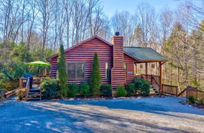 A log cabin with a chimney, a porch, and a covered outdoor seating area. - Cabin in Blue Ridge Hot Tub, Games, & Creek! (Blue Ridge)