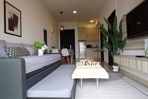 A modern living room with a sofa, a small table, and a potted plant. - Prestige Sky Riverfront (Kota Bharu)