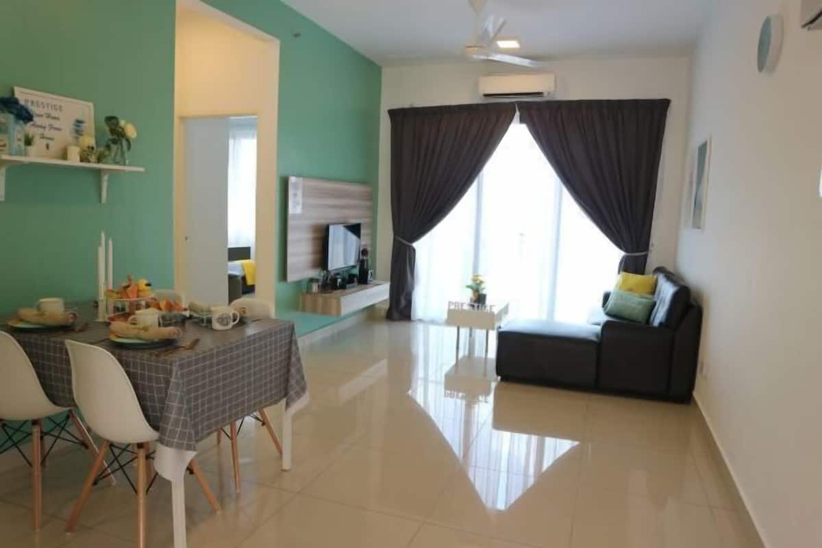 Una habitación con una mesa de comedor, sillas, un sofá, una televisión y un ventanal con cortinas.