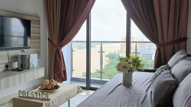 A bedroom with a bed, a TV, a table with a sign, and a view of the city. - Prestige Sky Riverfront (Kota Bharu)