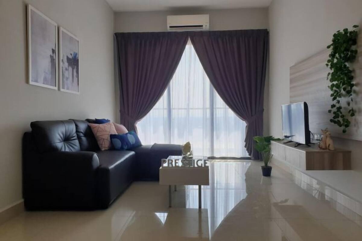Una sala de estar moderna con un sofá de cuero negro, una mesa de centro de vidrio y un televisor de pantalla plana.