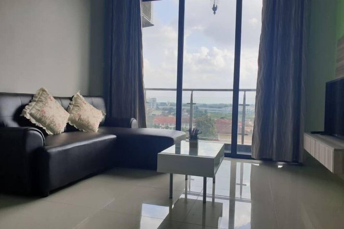 Una sala moderna con sofá, una mesa de centro y un ventanal con cortinas.