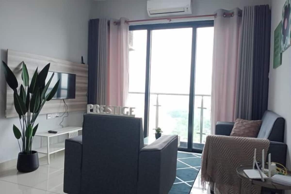 Una sala de estar moderna con un sofá, una mesa de centro, un televisor, una planta en maceta y un ventanal corredero que da a un balcón.