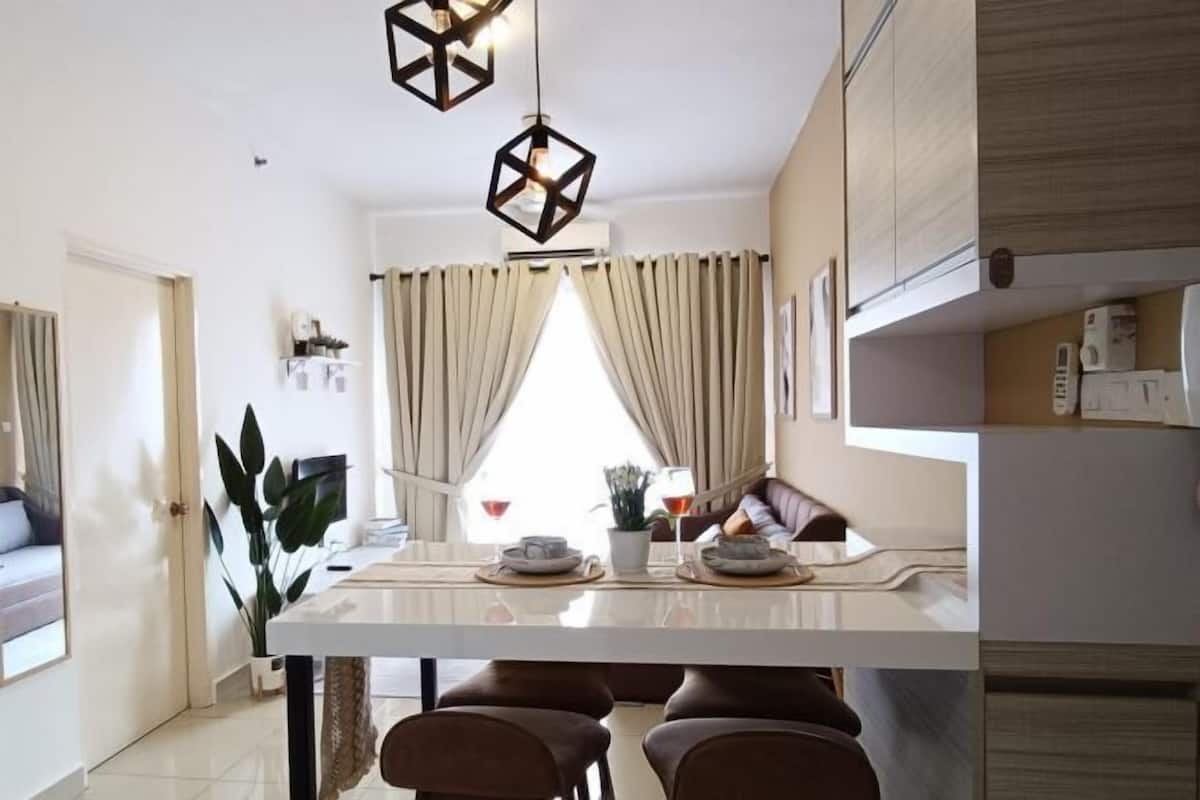 Una cocina moderna con una isla central, iluminación colgante y vistas al área de estar.