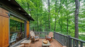 A wooden deck with outdoor seating, surrounded by a forest. - The Guest Cabin - Historic Home in Big Canoe (Big Canoe)