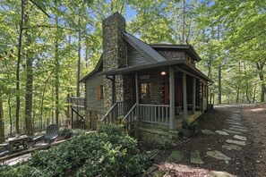A log cabin with a stone chimney, wooden porch, and a stone pathway leading to the entrance. - The Guest Cabin - Historic Home in Big Canoe (Big Canoe)