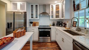 Una cucina moderna con mobili bianchi, elettrodomestici in acciaio inossidabile e pavimento in legno.