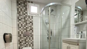 A bathroom with a glass-enclosed shower, a toilet, and a vanity with a mirror. - PABLO SUIT AVCILAR (Istanbul)
