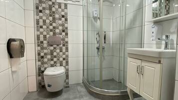 A bathroom with a glass-enclosed shower, a toilet, and a vanity with a mirror.