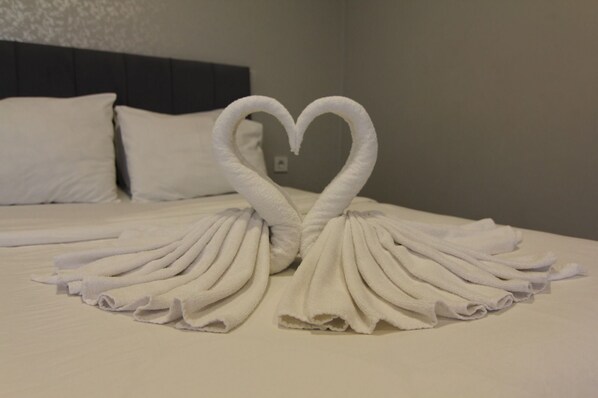 A bed with white linens and a heart-shaped towel arrangement. - PABLO SUIT AVCILAR (Istanbul)