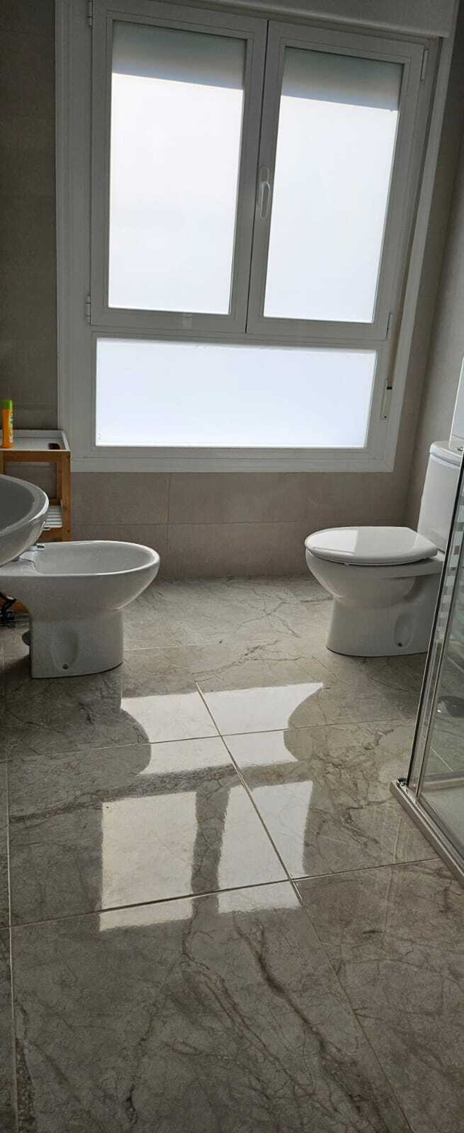 Ein Badezimmer mit Toilette, Bidet und einem großen Fenster.