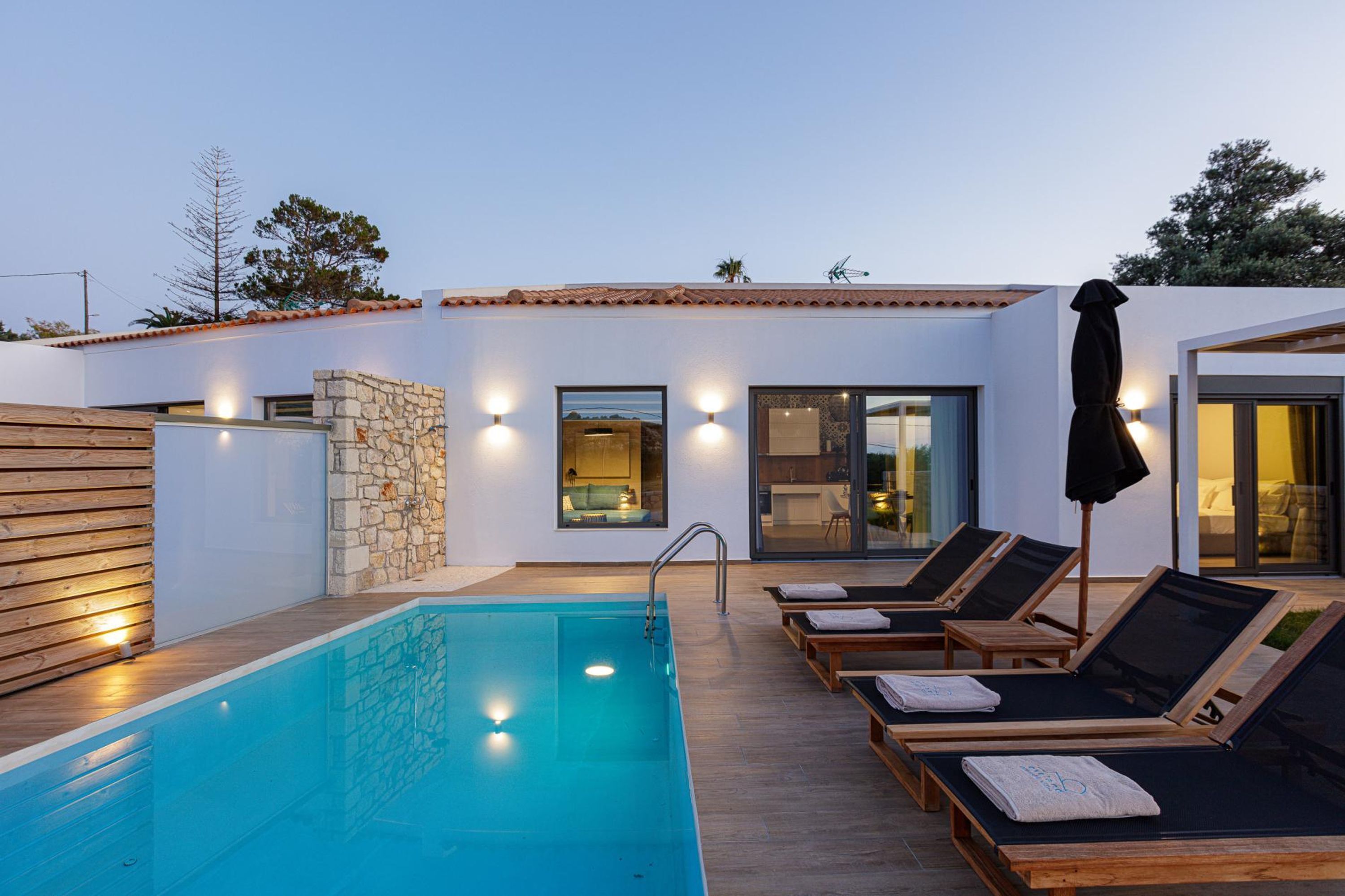 A modern outdoor pool area with lounge chairs and a stone wall.
