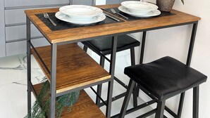 A modern kitchen with a microwave, stove, and sink. There is a dining table with chairs and a potted orchid. - Apto 1 dormitório no Brooklin (São Paulo)