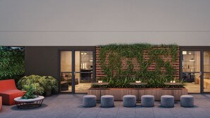 A modern outdoor seating area with red chairs and a central planter with greenery. - Apto 1 dormitório no Brooklin (São Paulo)