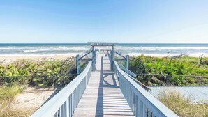 A wooden boardwalk leading to a beach with a covered viewing area.