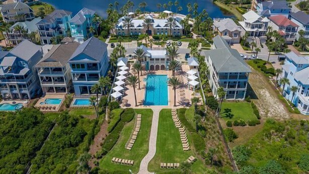 A resort with multiple buildings, a central swimming pool, and a lake.
