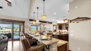 A spacious kitchen with a large island, bar stools, and a view of the outdoors.