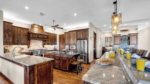 A spacious kitchen with wooden cabinets, a large island, stainless steel appliances, and a breakfast bar.