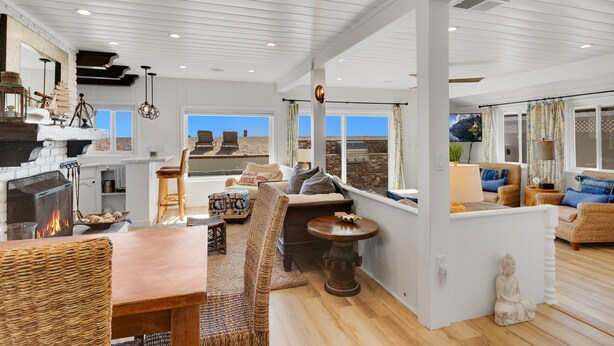 Un amplio espacio de sala con chimenea, muebles de mimbre y vista a la playa.