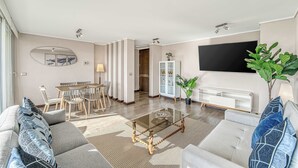 A living room with a sofa, coffee table, TV, and dining area. - Costa Vina 3B  Balcony & View (Viña del Mar)