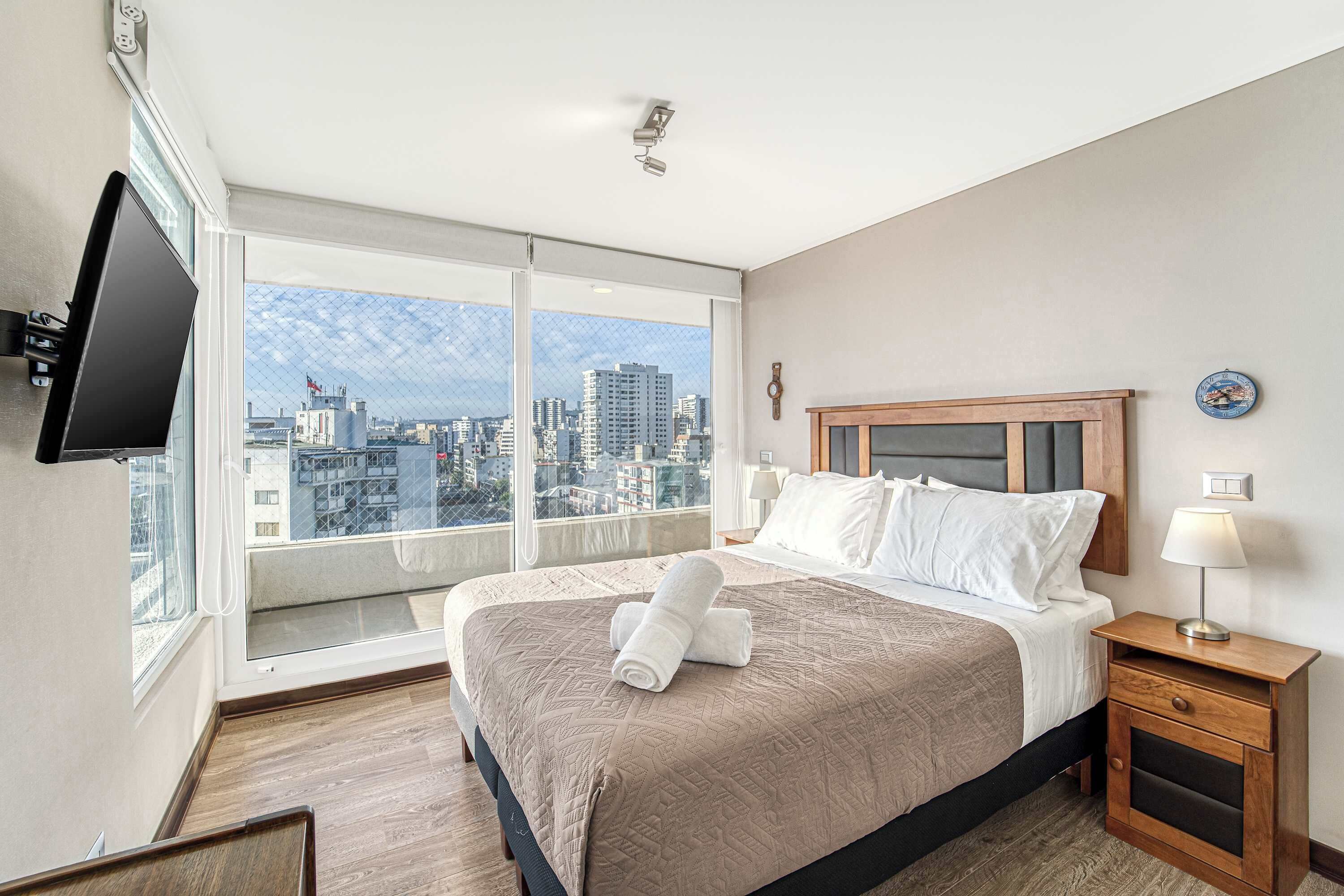Een hotelkamer met een groot bed, een nachtkastje, een televisie en uitzicht over de stad.