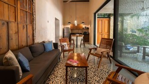 Un salon confortable avec un canapé, des fauteuils, une table basse et une cuisine en arrière-plan.