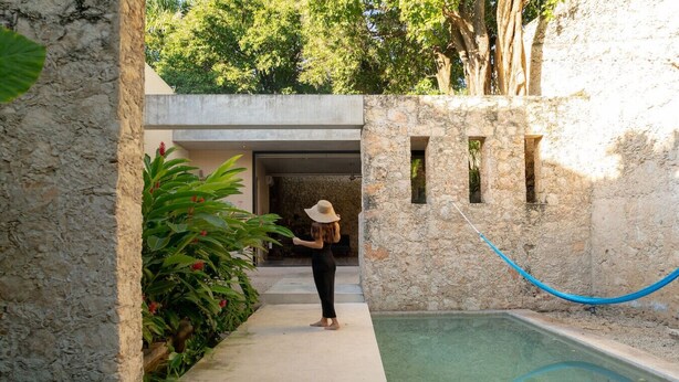 Un espace piscine avec un mur en pierre, une corde bleue et une personne tenant un appareil photo.
