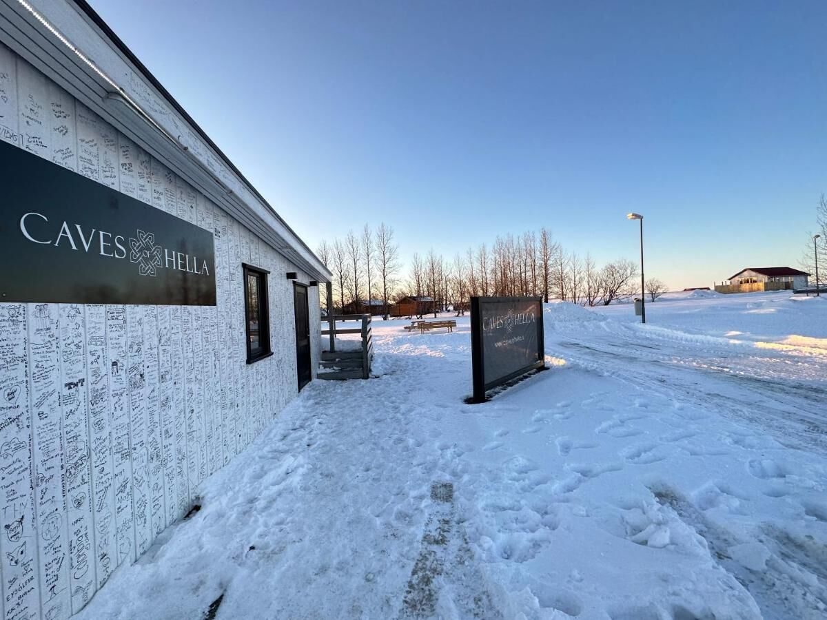 A building with a sign reading "CAVES HELL" and a covered outdoor area with snow on the ground.