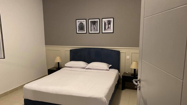 Una camera d'albergo con un letto grande, due comodini con lampade e tre quadri appesi al muro.