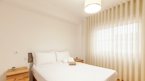 Ein ordentlich eingerichtetes Schlafzimmer mit einem Bett, Nachttischen aus Holz und einer kleinen Pflanze.