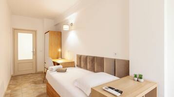 A hotel room with a bed, bedside table, lamp, and a door.