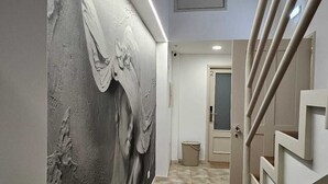 Ein Flur mit Wandmalerei, strukturierter Wand, gefliestem Boden und einer modernen Treppe.