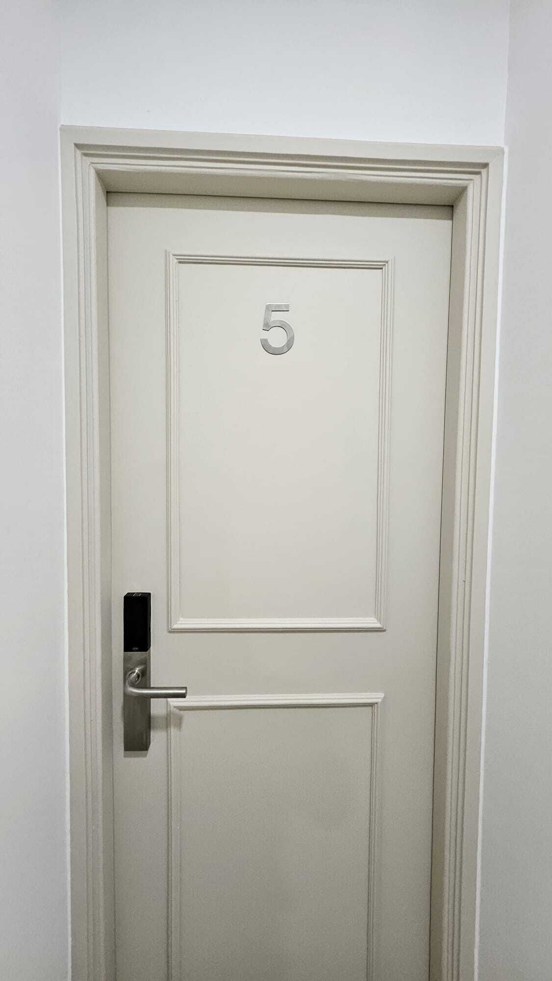 A white door with the number 5, a modern handle, and a small rectangular panel.