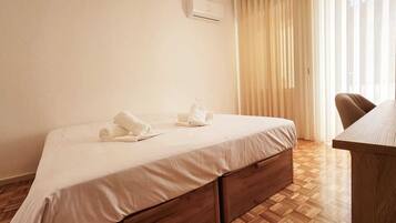 Una habitación de hotel con una cama, un escritorio de madera y una ventana con cortinas.