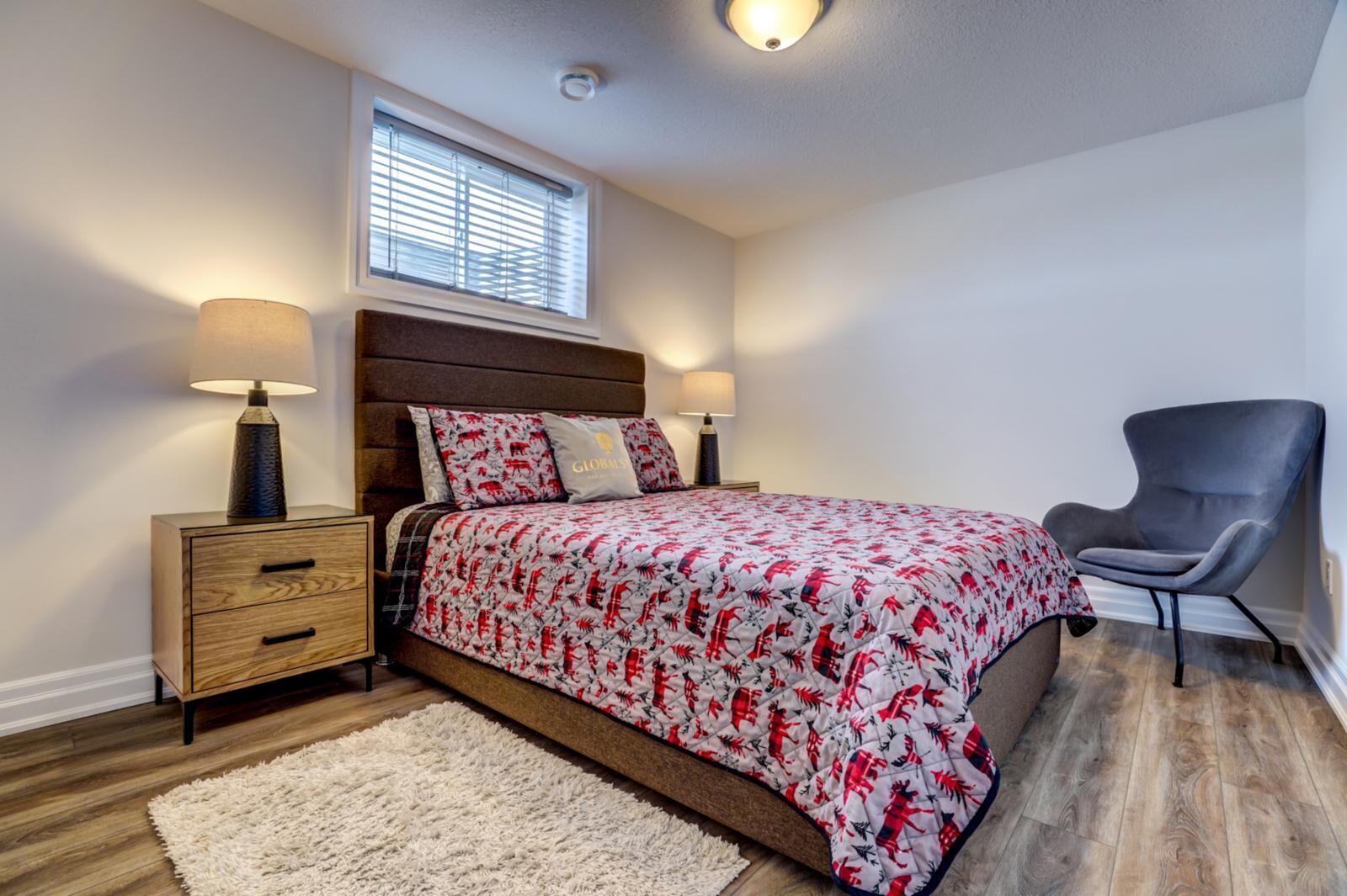 A bedroom with a bed, bedside tables, a chair, a window, and a ceiling light.