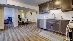 A modern kitchen with wooden cabinets, a dishwasher, and a dining area with a table and chairs. - GLOBALSTAY New Basement 4Bd in Port Elgin. Close to the Beach (Port Elgin/Canada)