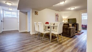 A spacious living area with a dining table and chairs, a sofa, and a television. - GLOBALSTAY New Basement 4Bd in Port Elgin. Close to the Beach (Port Elgin/Canada)