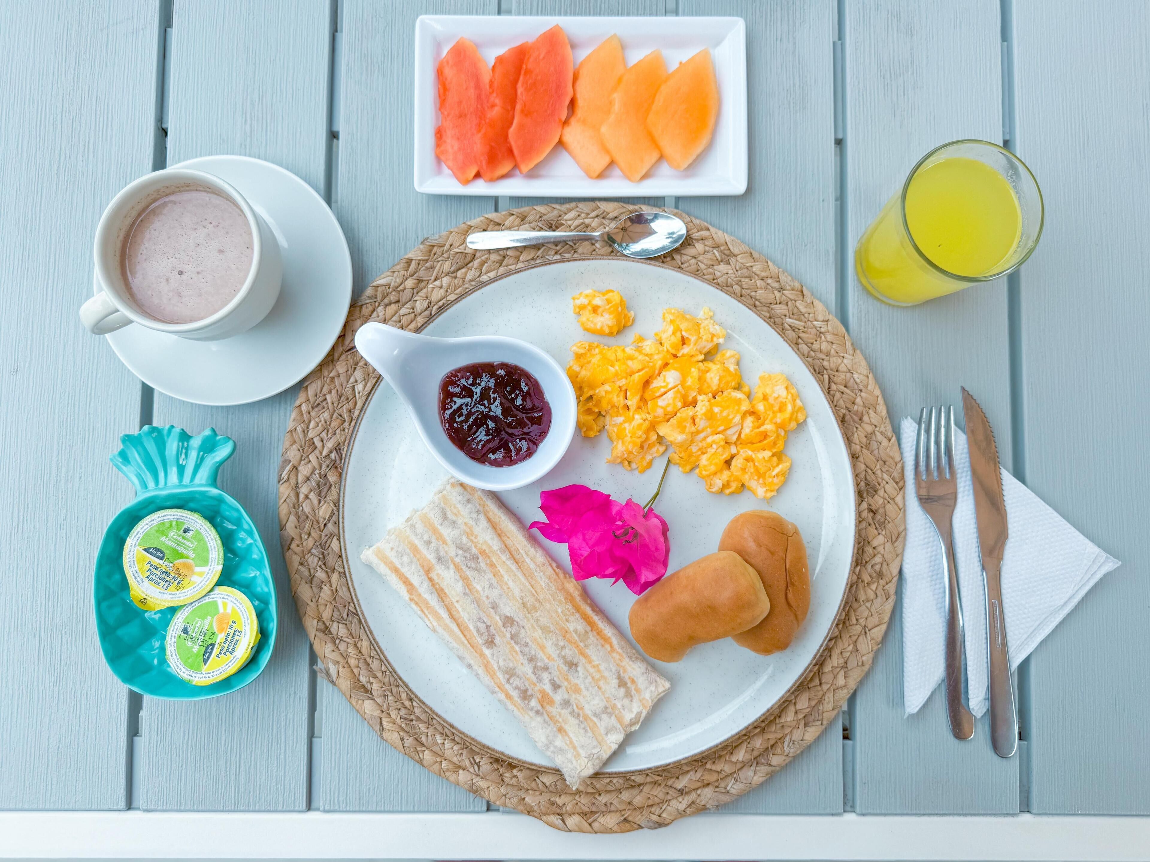 A breakfast plate with scrambled eggs, toast, jam, and a cup of coffee.