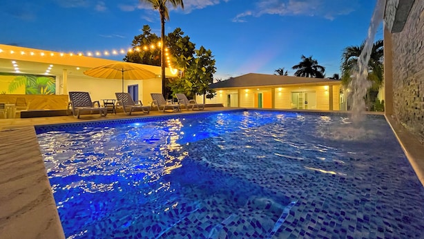 A swimming pool with a tiled deck, lounge chairs, and a palm tree. - Zaba Beach House (San Andrés)