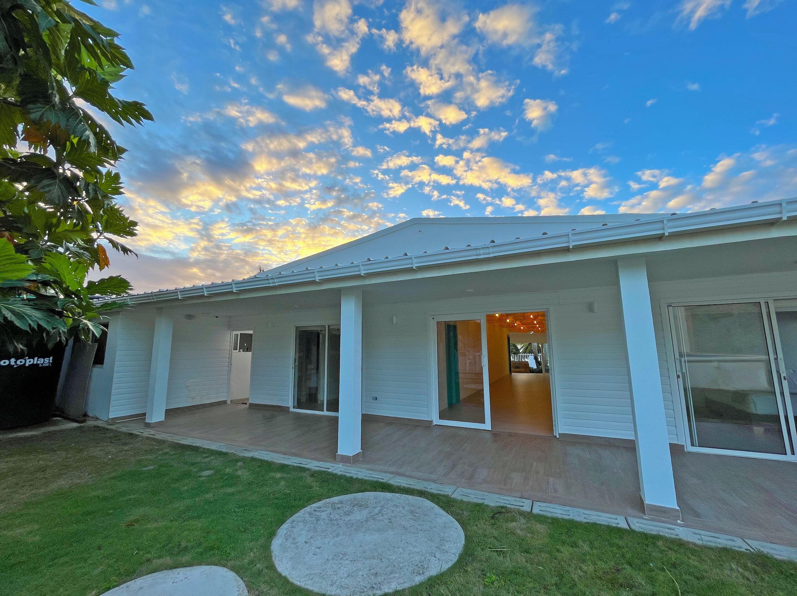 Einbungalow mit überdachter Terrasse, großen Fenstern und einem gepflegten Rasen.