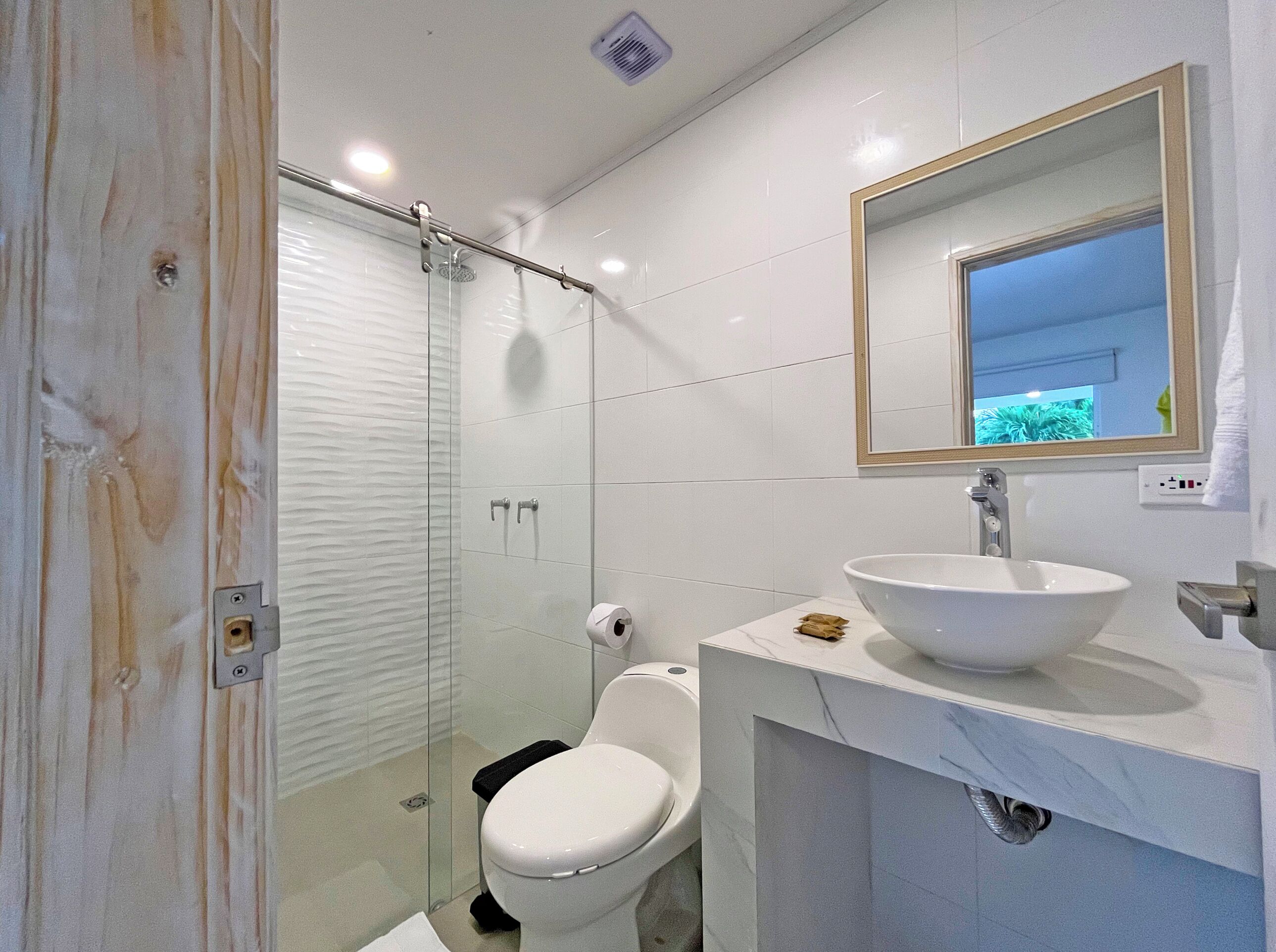A modern bathroom with a glass-enclosed shower, a white toilet, and a marble vanity with a large sink.