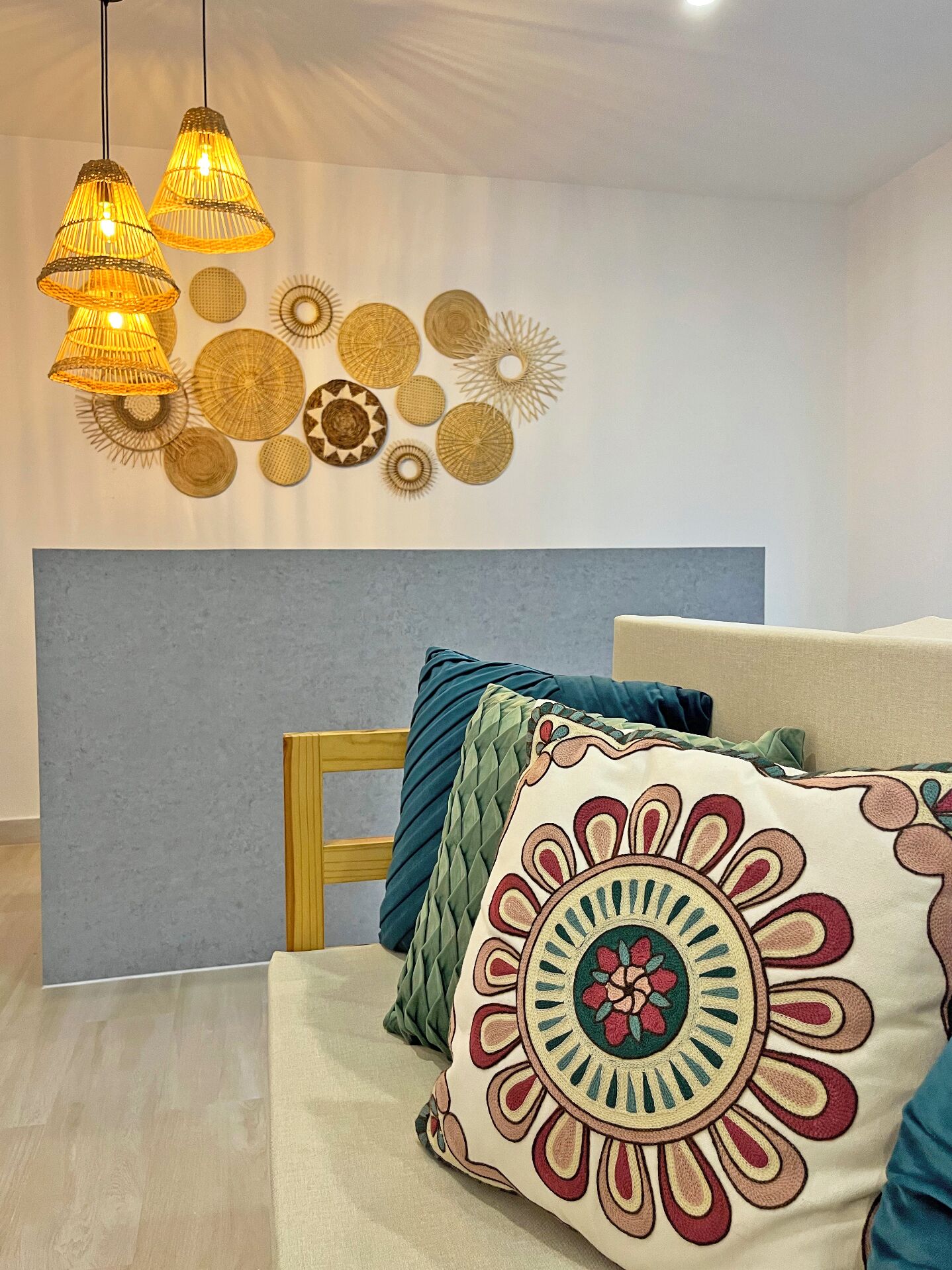 Un dormitorio con una cama, cabecera y un muro decorado con cestas tejidas.