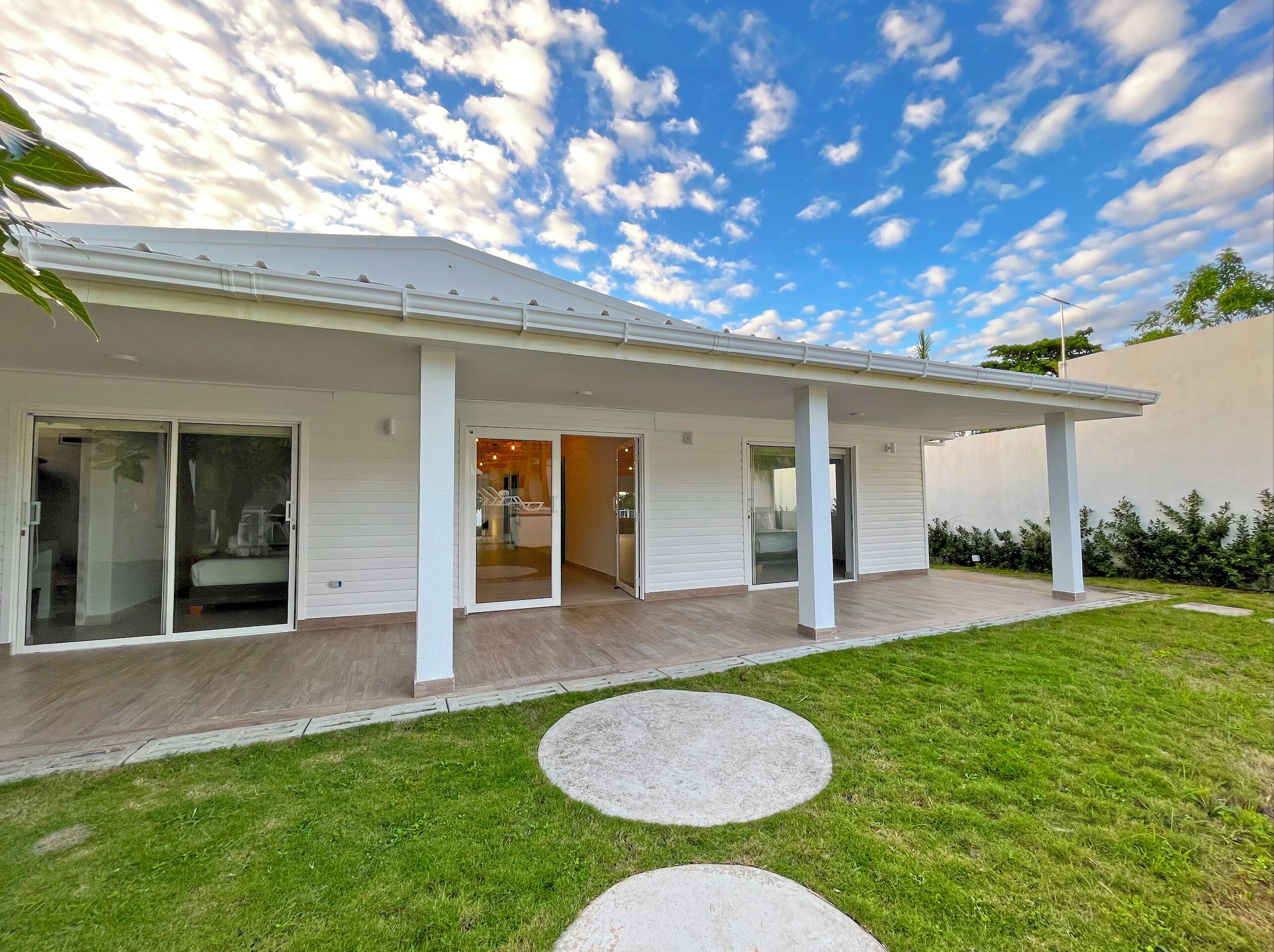 A modern house with a covered porch, sliding glass doors, and a well-maintained lawn.