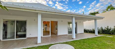 A modern house with a covered porch, sliding glass doors, and a well-maintained lawn.