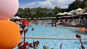 Zona de piscina con sillones de descanso y sombrillas.